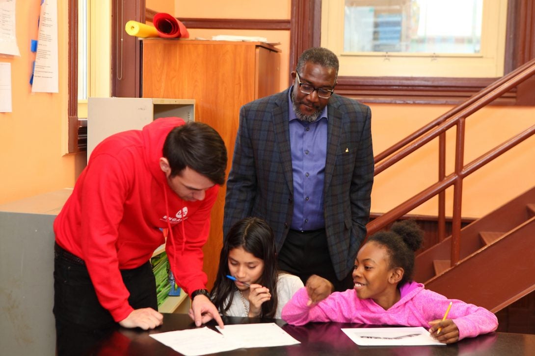 UIC student tutors young children while Professional staff member watches