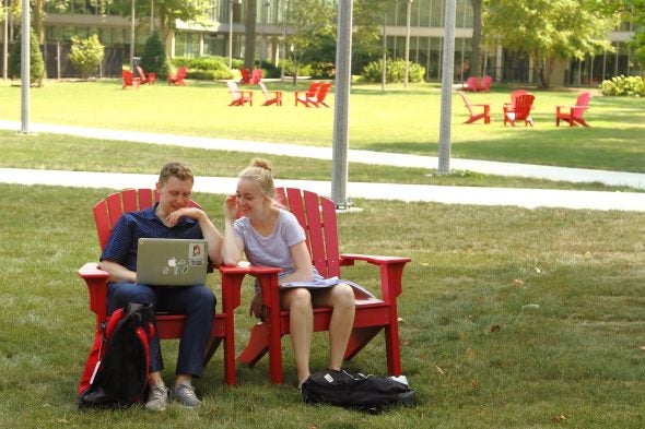 Students relax on red Adirondack chairs