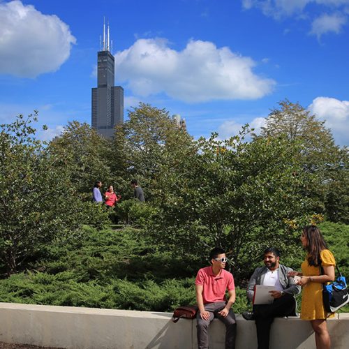 3 students sitting in the sunshine, willis tower in the background