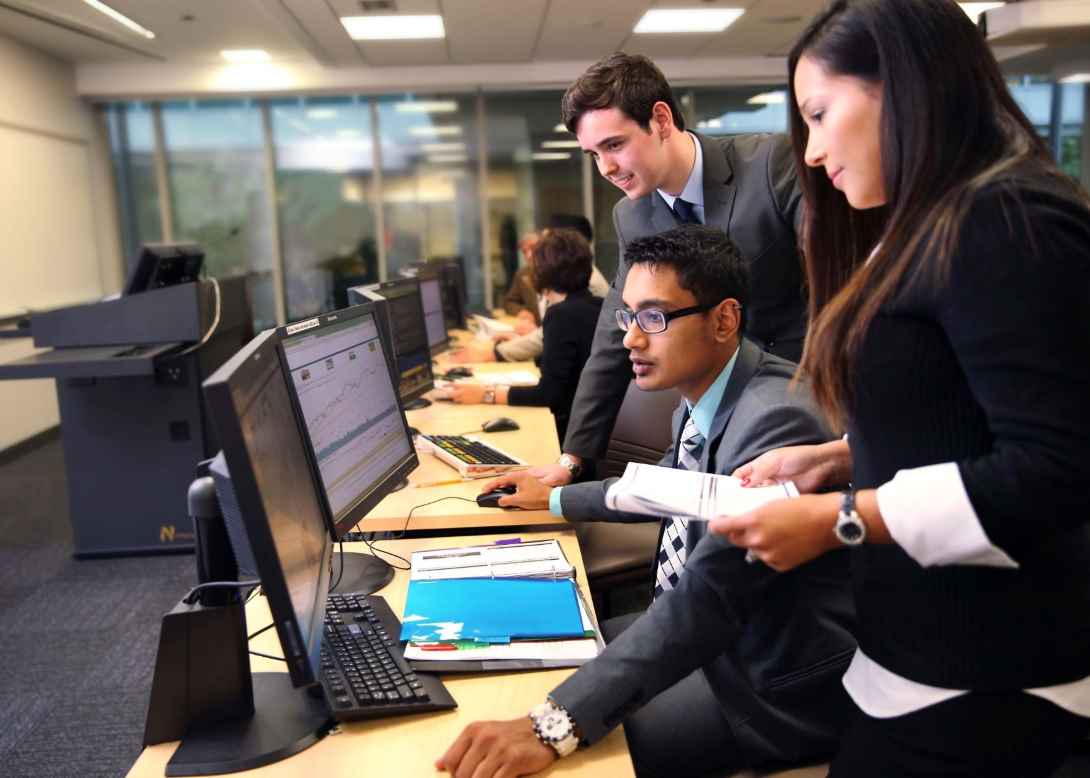 three students in business suits looking at a computer